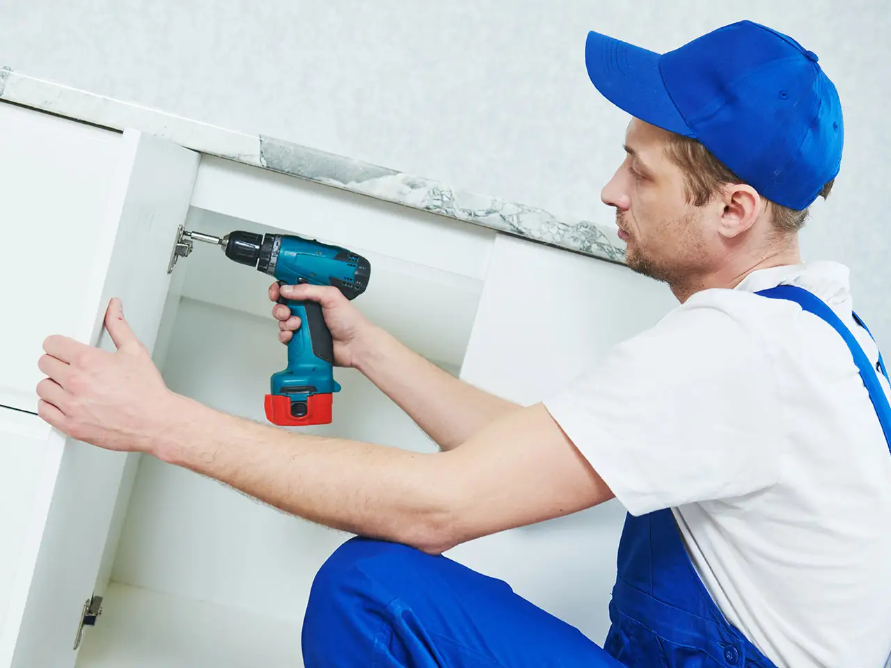 Ein junger Mann mit Arbeitskleidung bei der Küchenmontage
